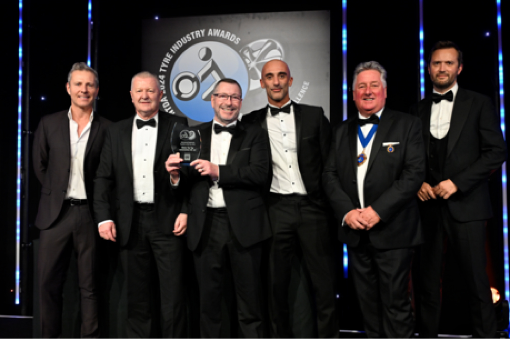 6 men in suits on an event stage with an award in their hands